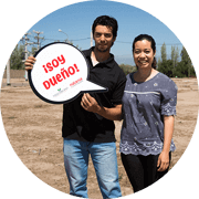 Pareja enfrente del lote, con un cartel que dice soy dueño